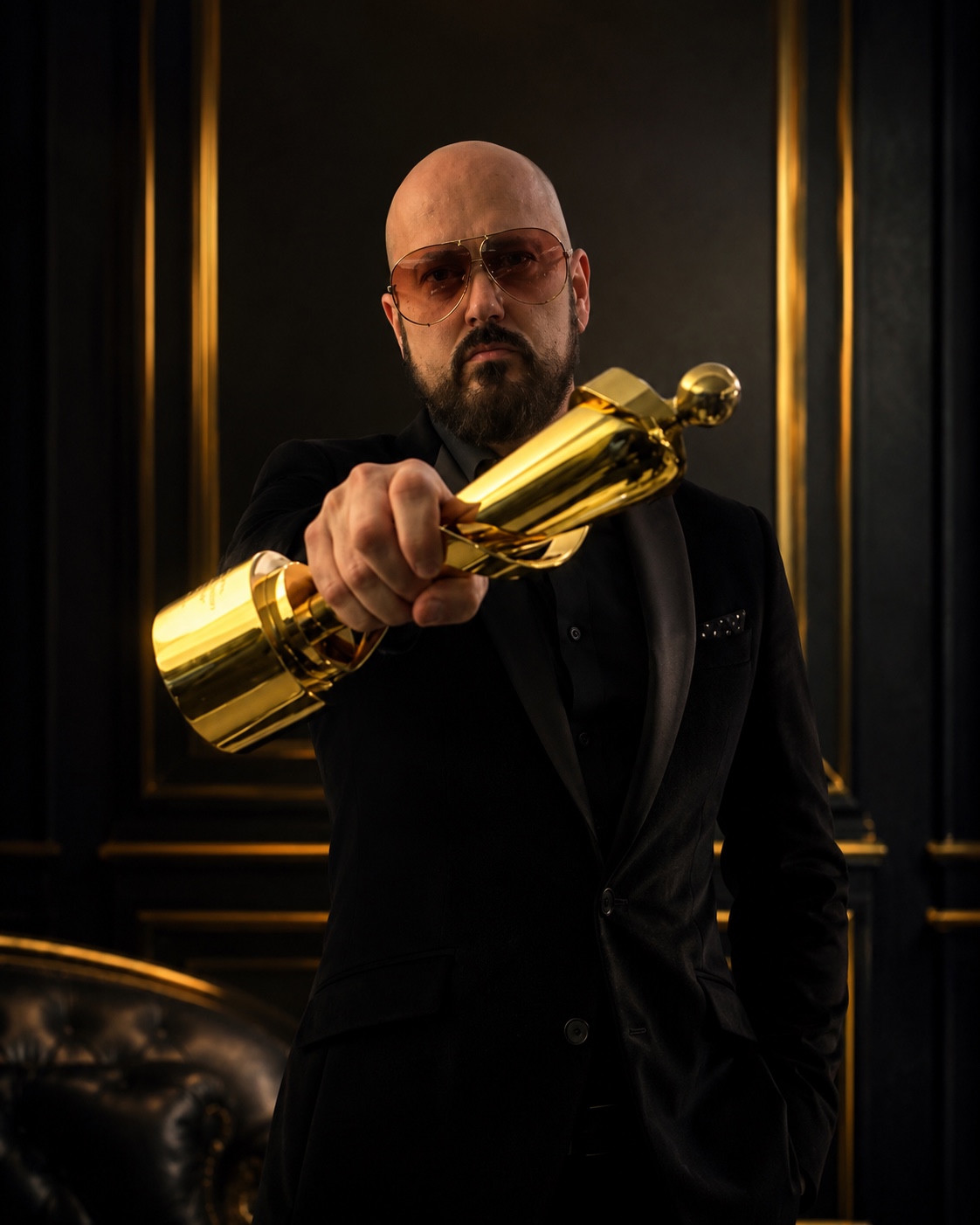 Dub J in a black suit holding his JUNO trophy toward the camera